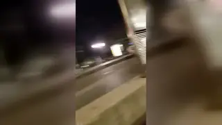 Two Men Embrace Passionately at a Tram Stop