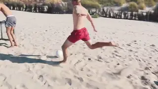 Fit Guys in Uniform Kick Ball on Sandy Beach