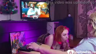 Redhead Swallows Him Deep While the TV Plays On