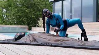 European Domme Teases Bound Sub in Latex Catsuit Outdoors